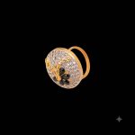 Large circular brass statement ring featuring gold and white dual-tone finish with a black floral stone design in the center