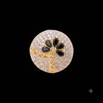 Large circular brass statement ring featuring gold and white dual-tone finish with a black floral stone design in the center