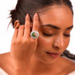 Large circular brass statement ring featuring gold and white dual-tone finish with a green floral stone design in the center